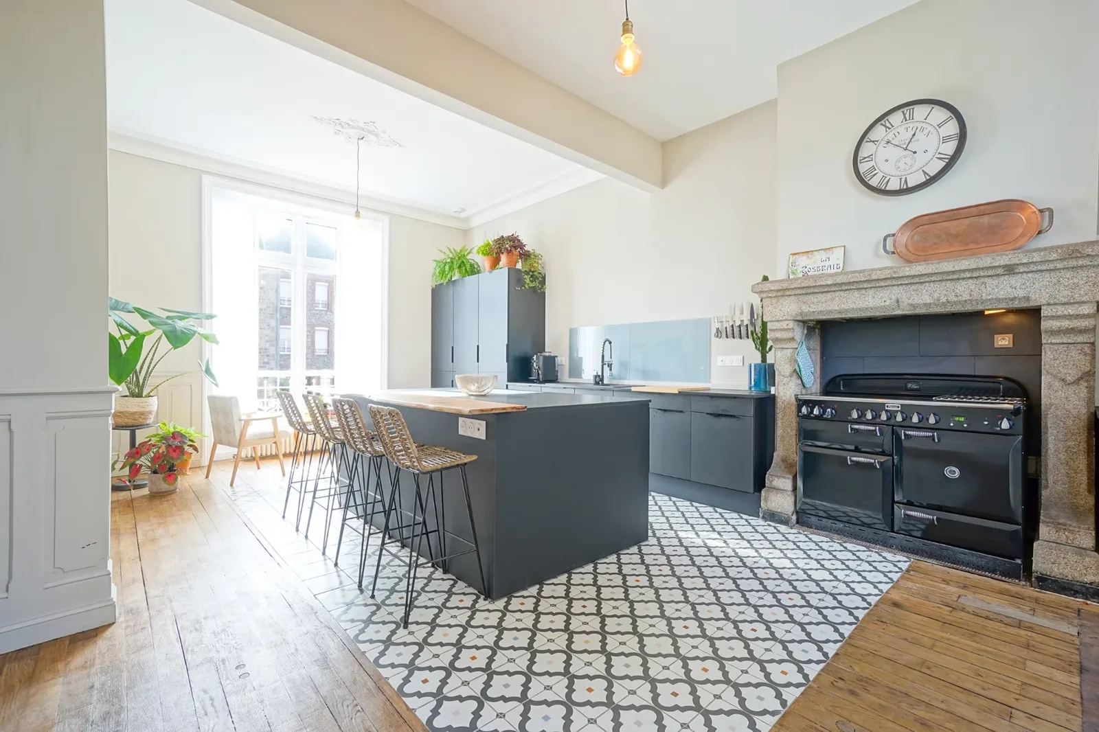Cuisine du Manoir Ducey avec piano de cuisson, cheminée de granit et îlot central