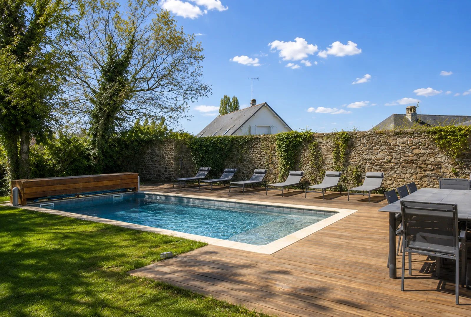 Piscine chauffée, terrasse en bois et transats dans le jardin clos du Manoir Ducey