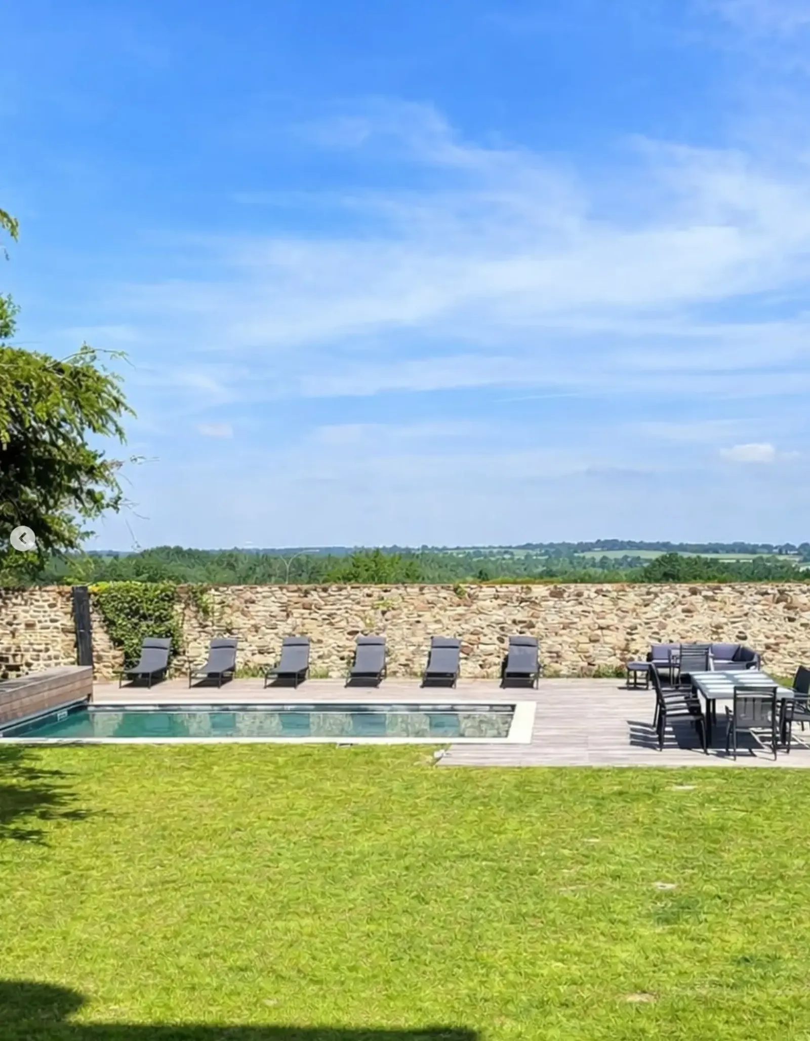 La piscine chauffée et la pelouse bordées du mur de pierre, ouvertes sur la campagne normande au Manoir Ducey